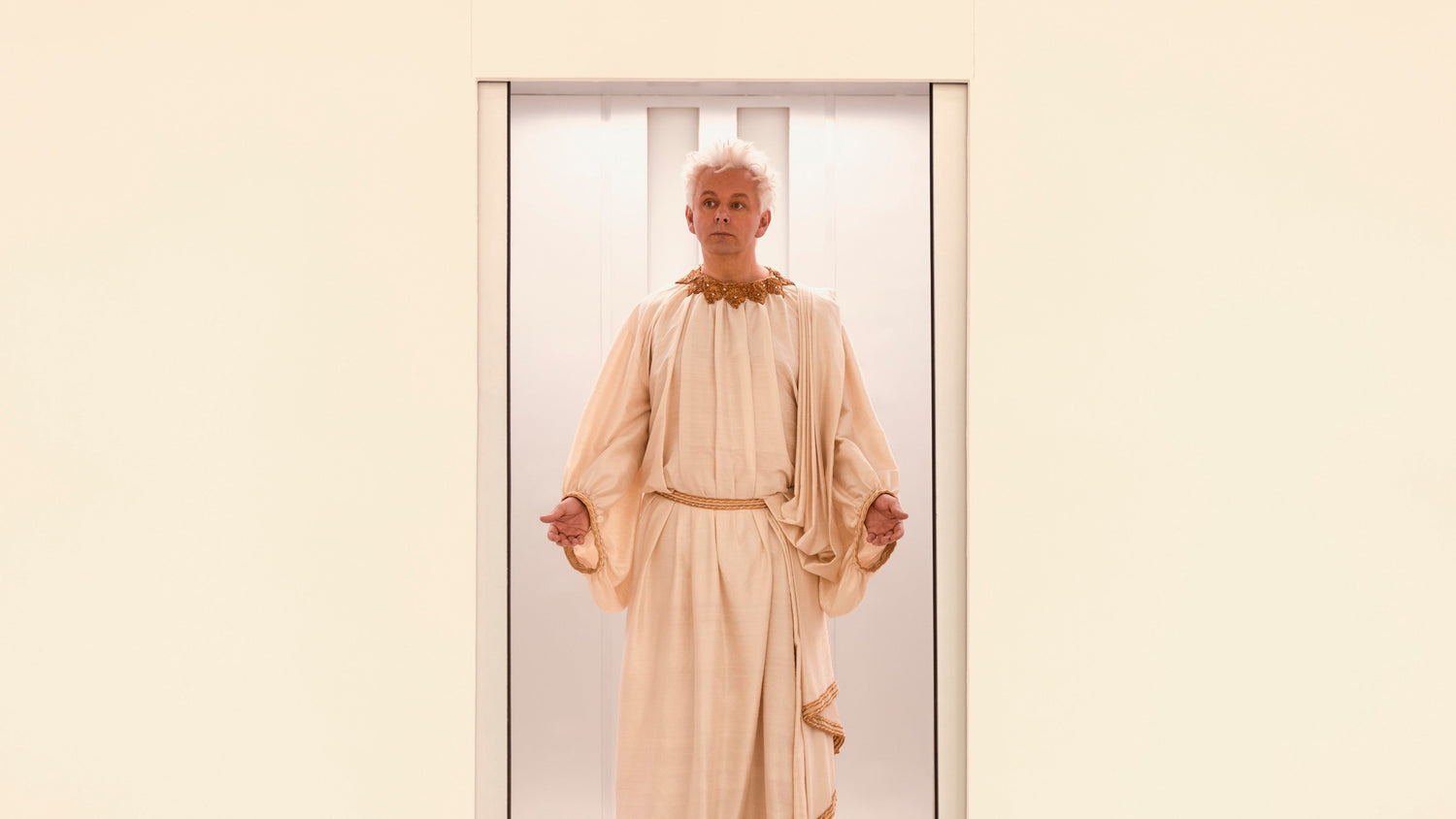 A photo of angelic Aziraphale emerging from an elevator.