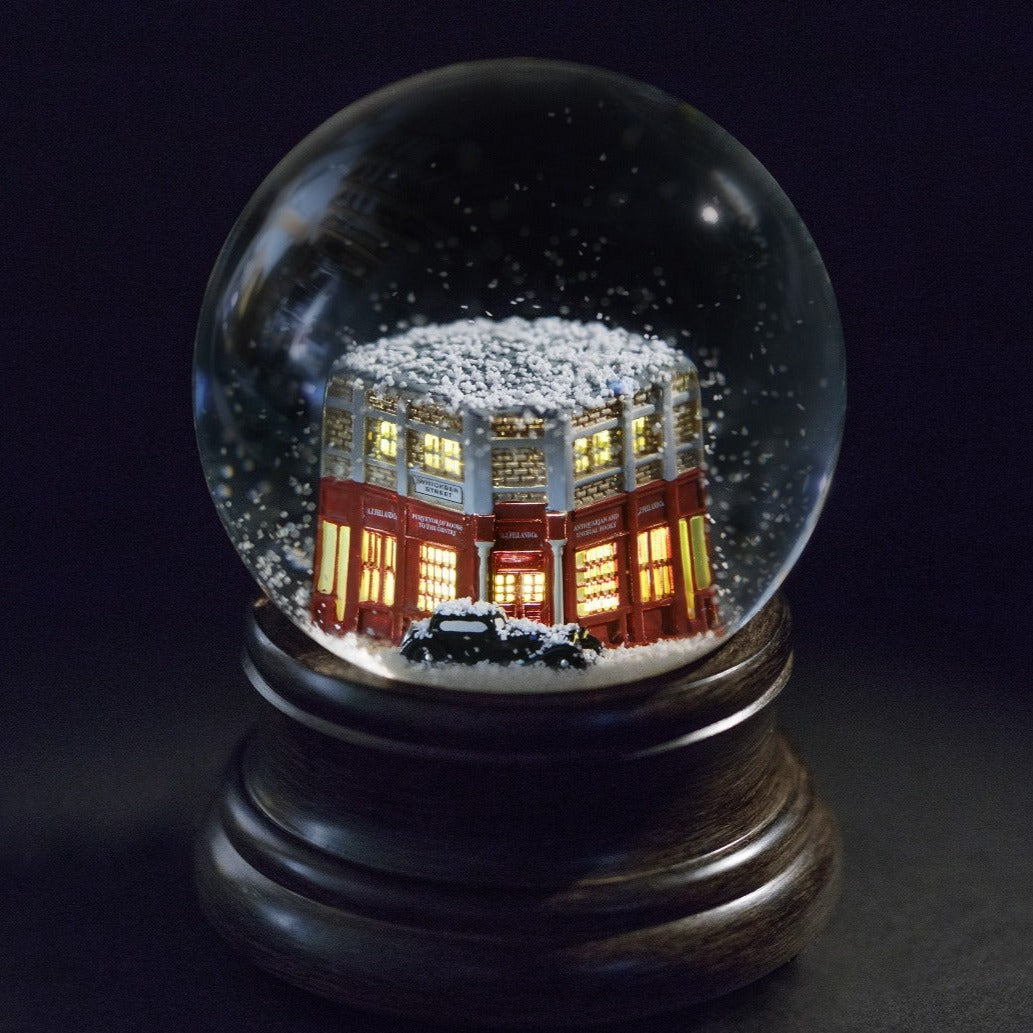 Snowglobe featuring Crowley's Bentley and Aziraphale's bookshop, photographed against a black background.