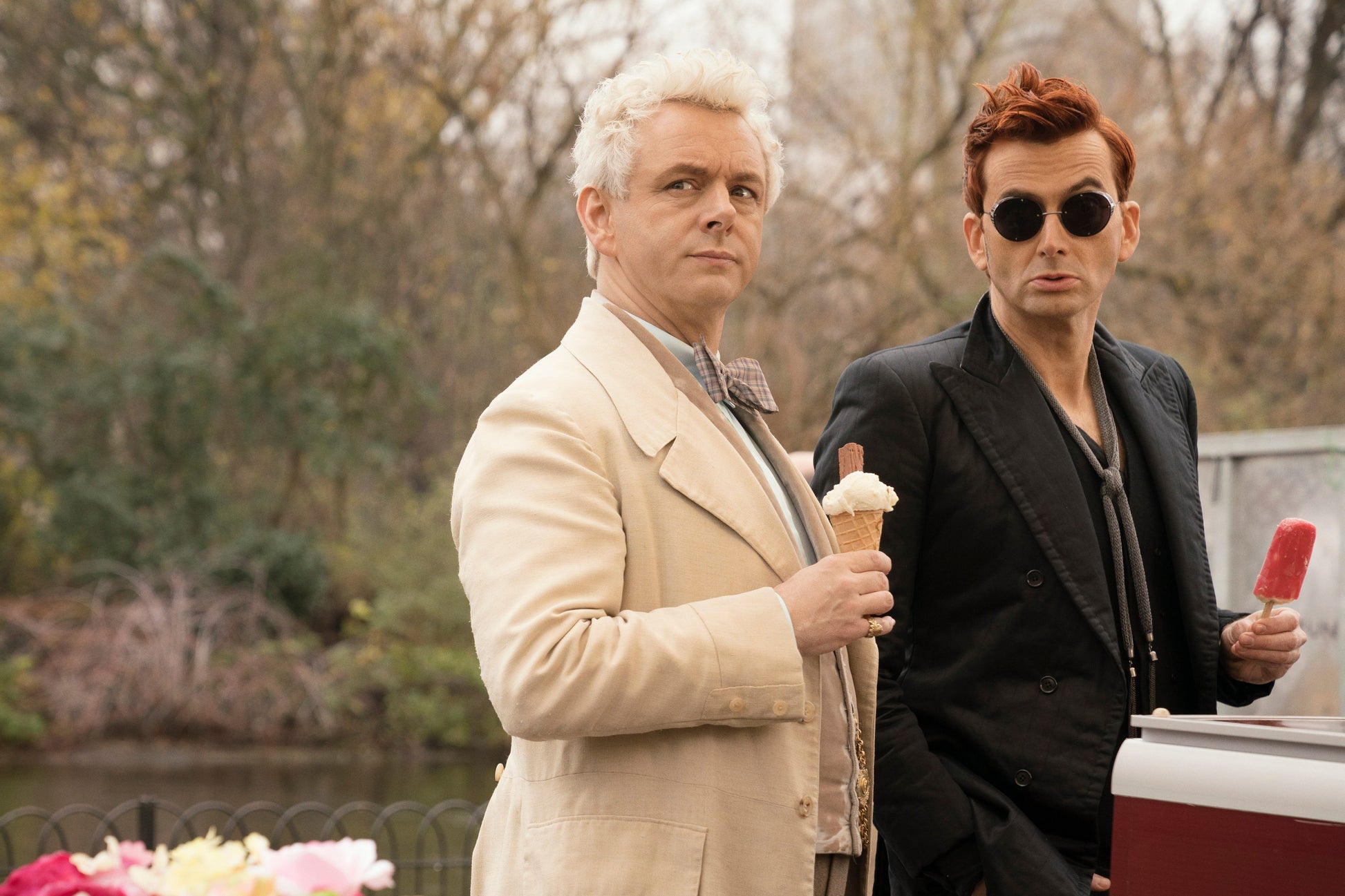 Aziraphale and Crowley looking off into the distance while enjoying some ice cream.