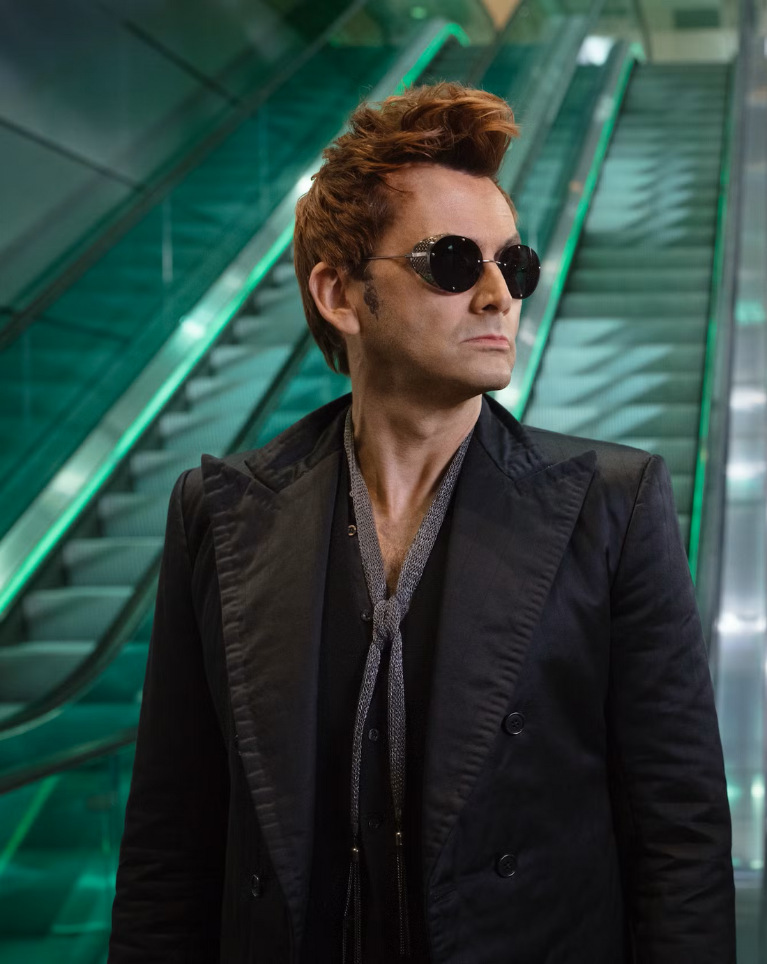 Crowley standing at the bottom of an escalator looking to his left.