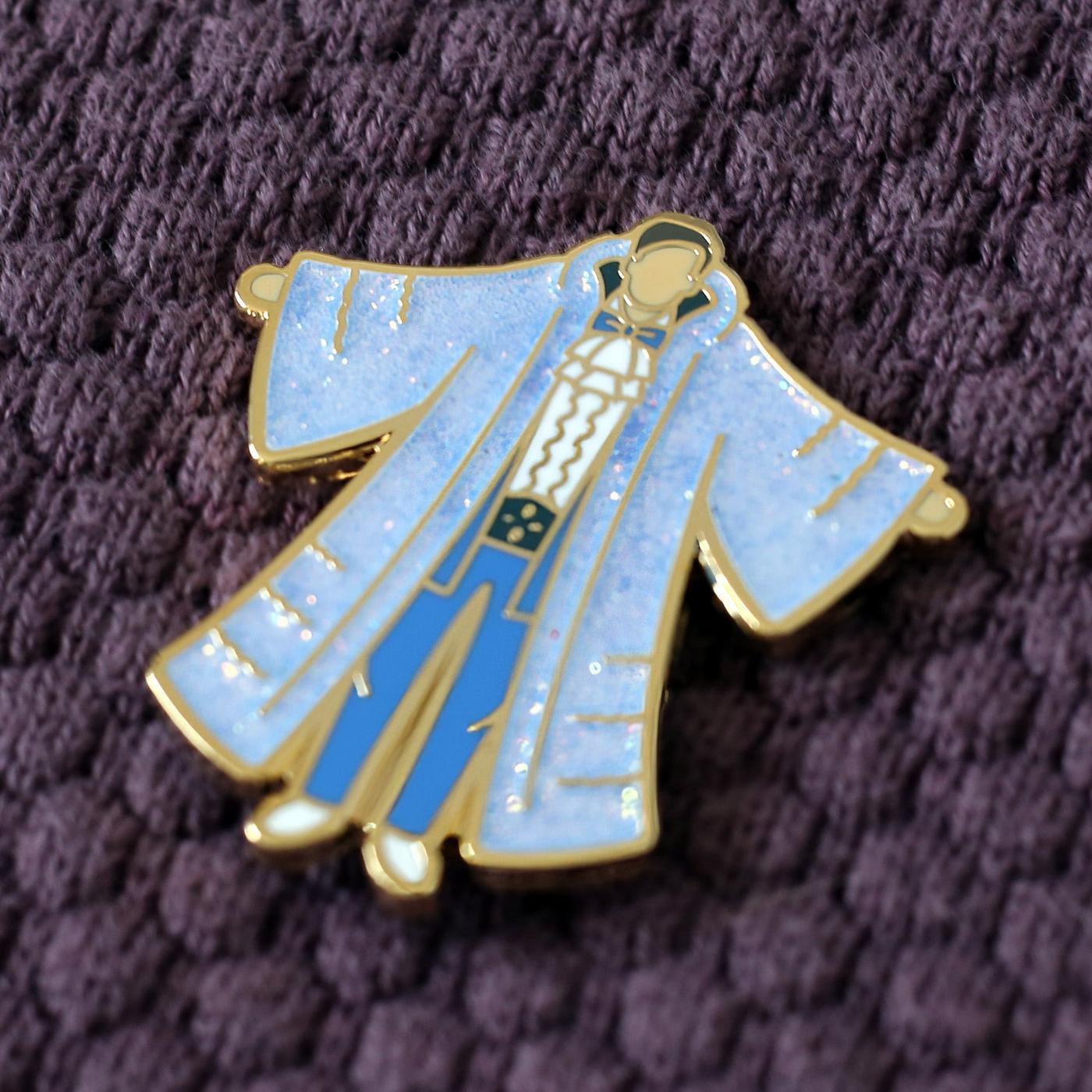 Photograph of a Good Omens enamel pin on a fabric background: Jim (Fabulous)