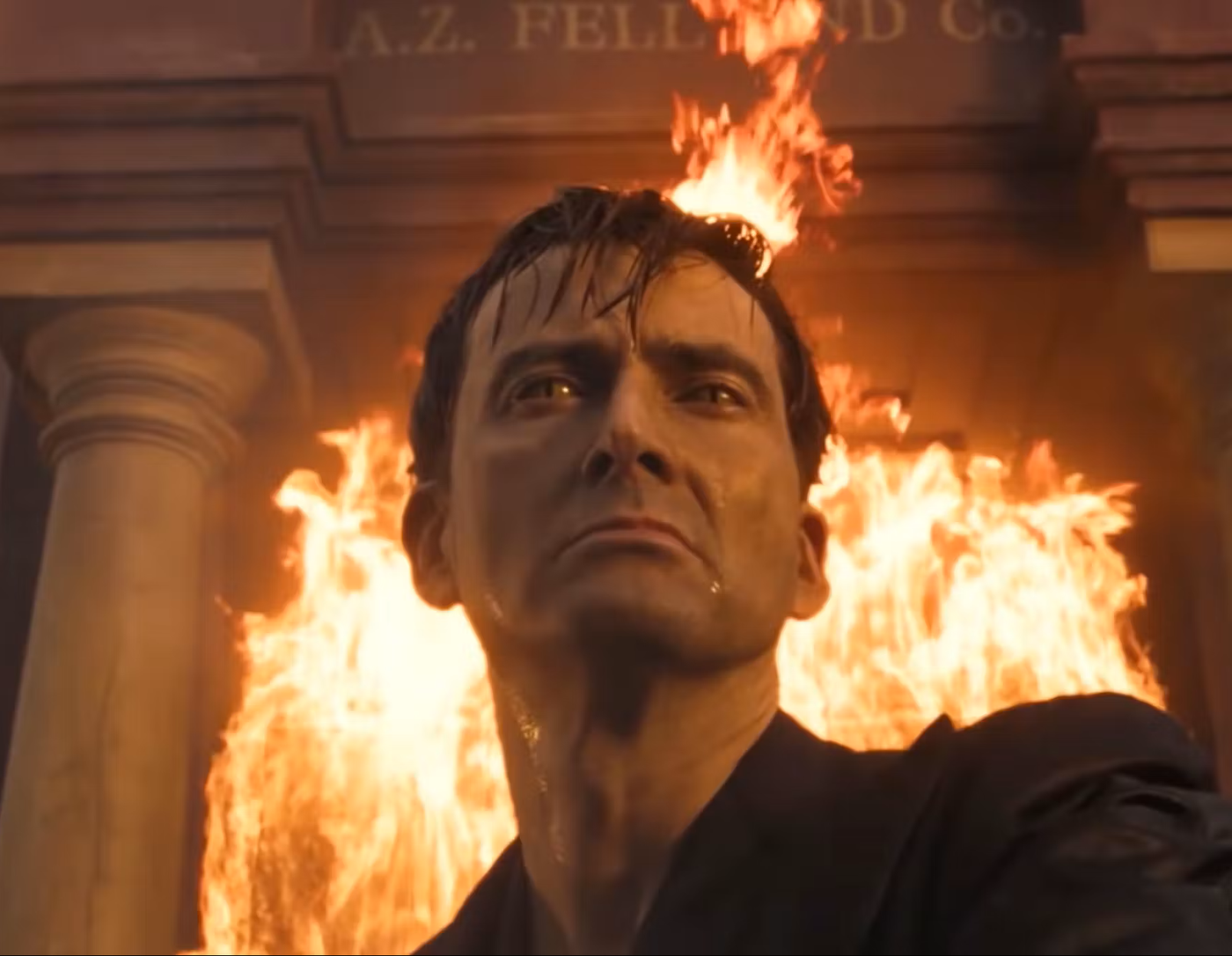 Crowley standing in front of the burning bookshop.